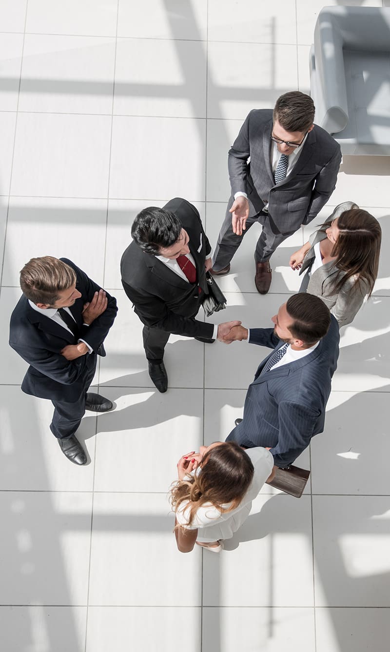 An overhead view of a group of business professionals standing in a modern office environment, engaged in conversation and networking.