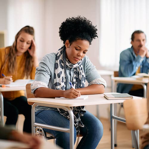 Woman in classroom writing notes in a notebook